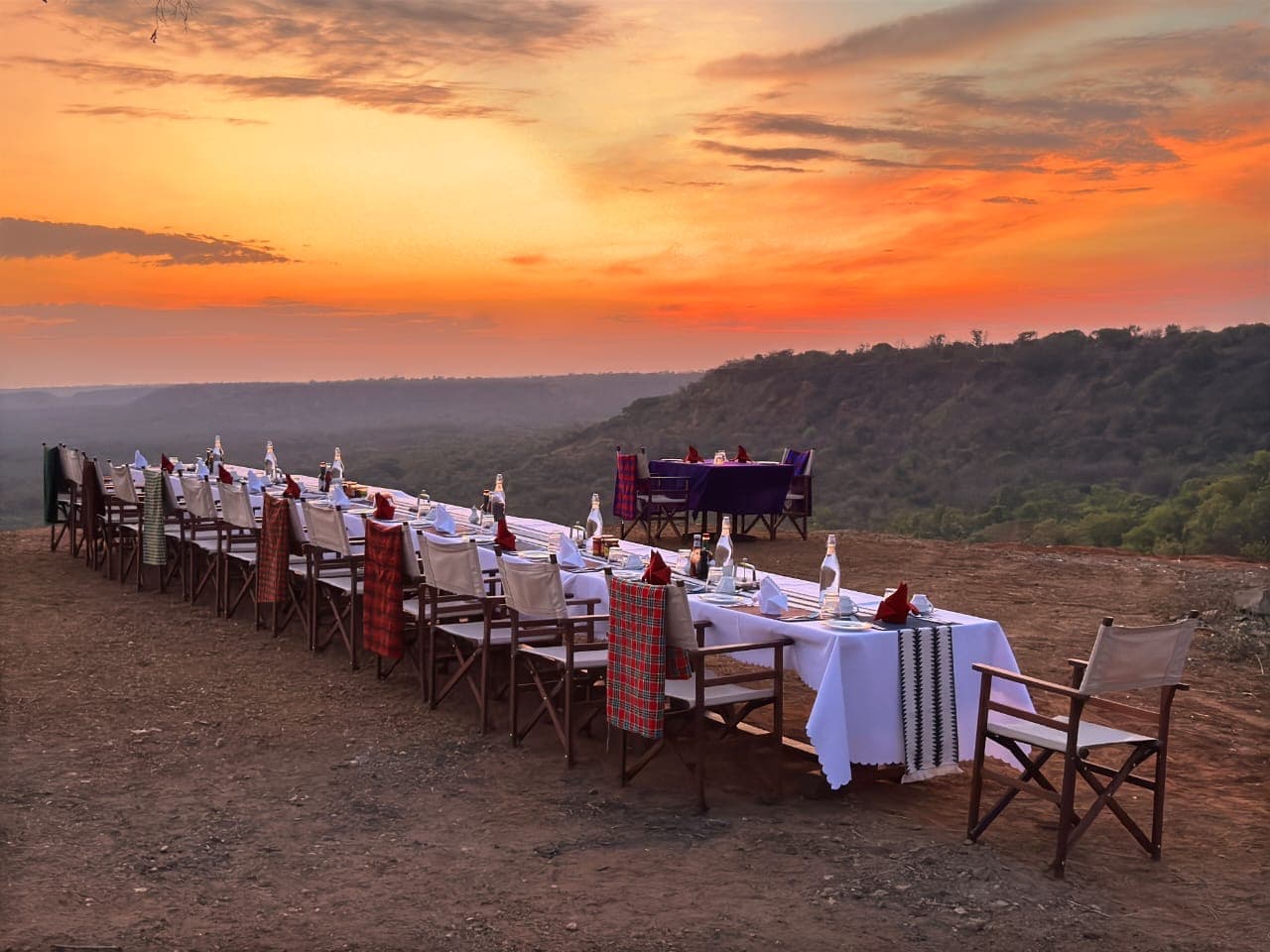 A long table laid for dinner as the sun drops behind the escarpment